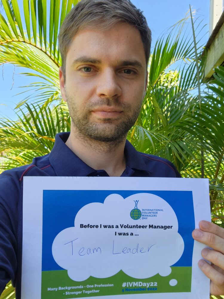 A selfie of Alex Weber, program manager for Braking the Cycle holding a sign that reads 'before I was a volunteer manager I was a Team Leader'