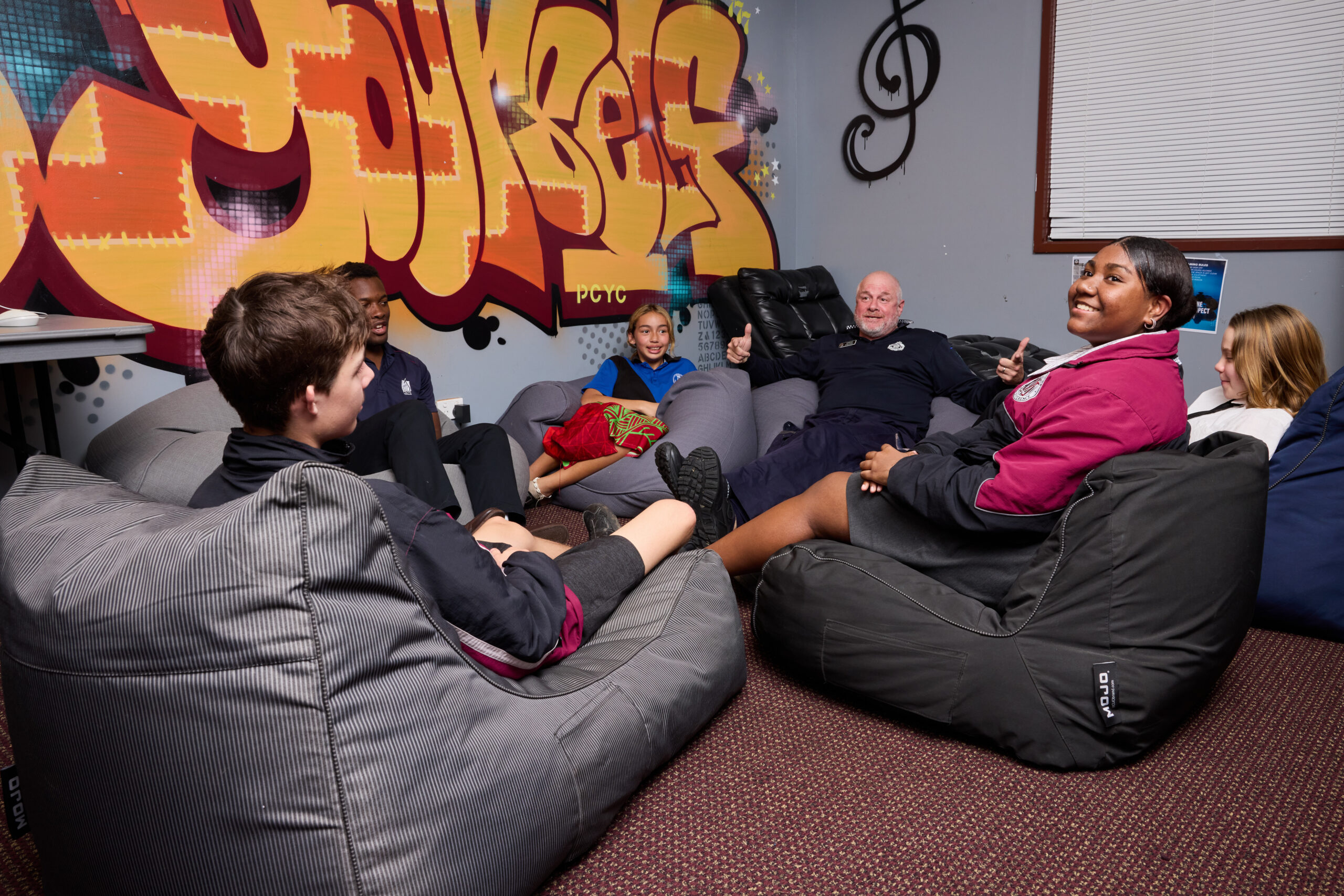young people and police officer sitting on bean bags chatting