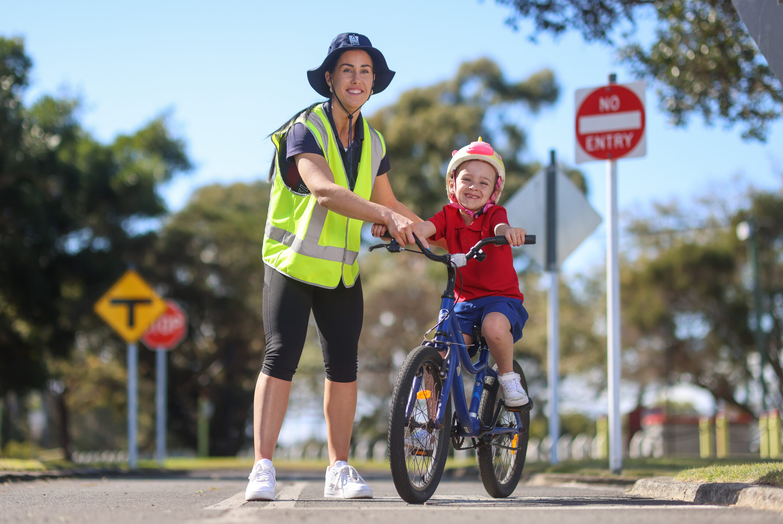 woman in high vis assisting young child on bike