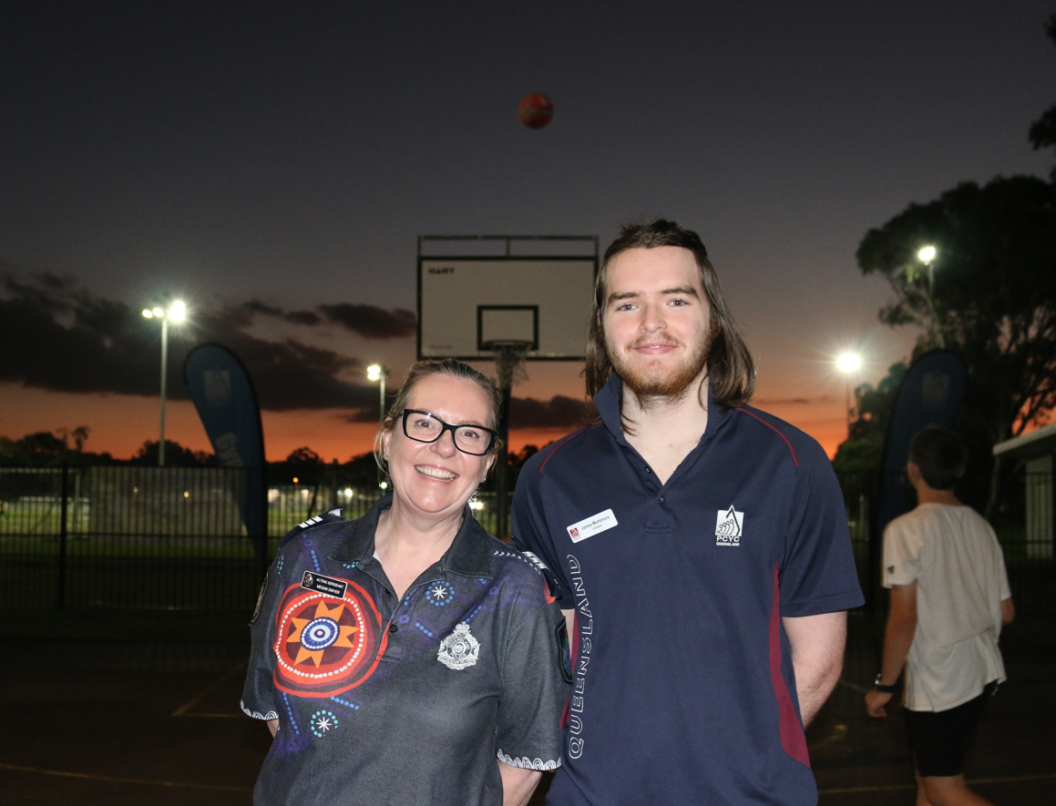 A Police Officer and Volunteer mentor smiling outside an after dark basketball session
