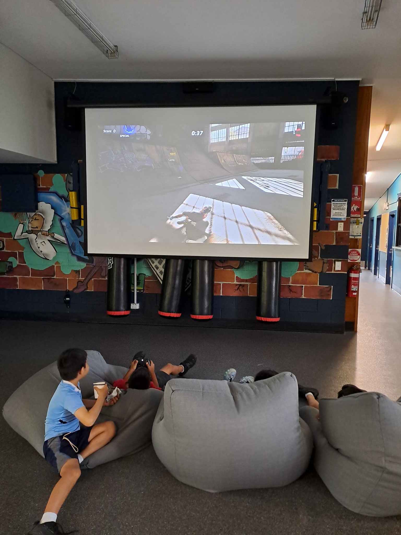 Young people playing video games on a projector during our Drop In program