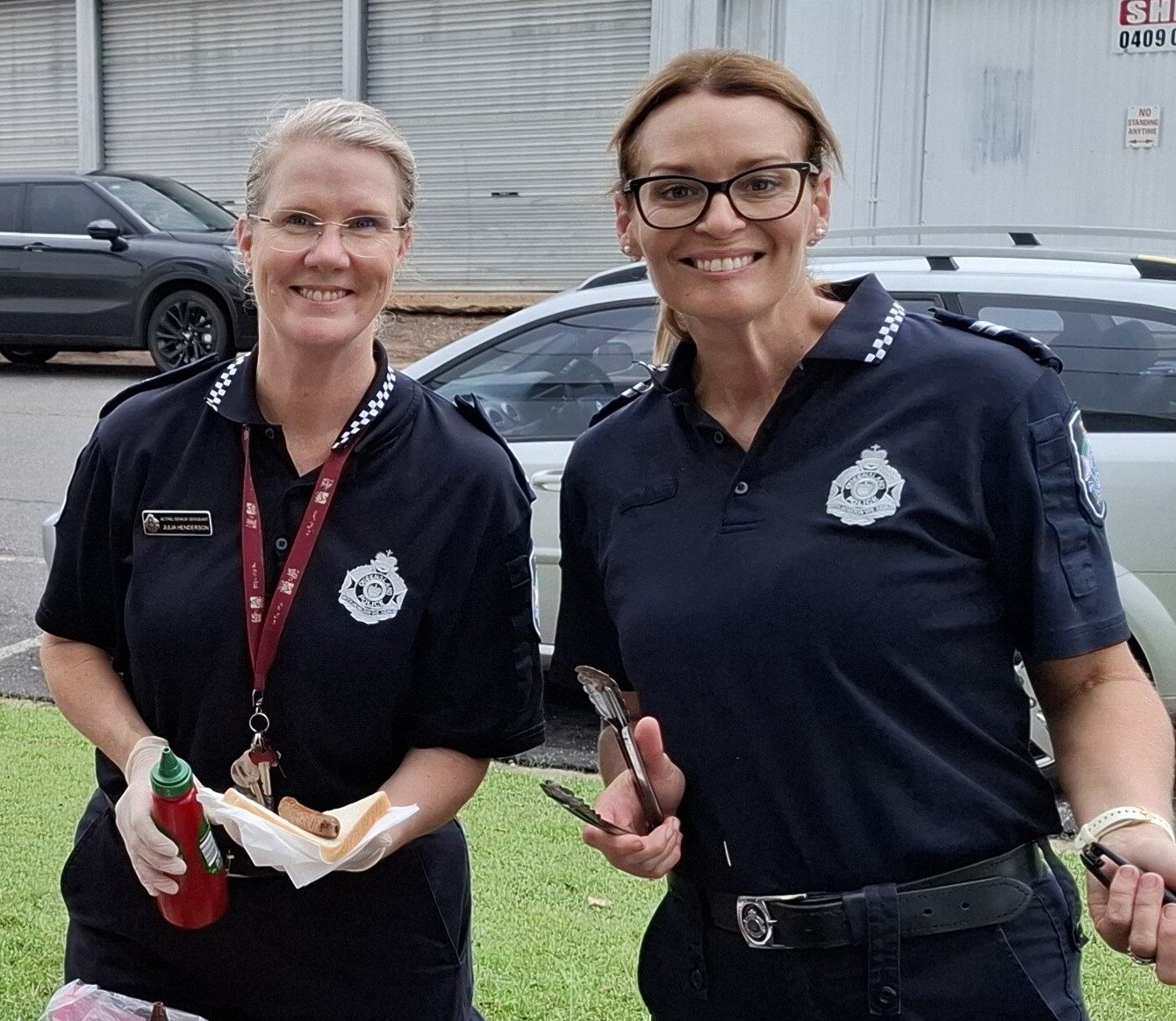Two police officers serving up sausages on bread for our Drop In program
