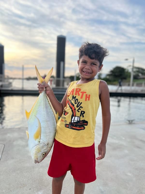 Young person holding giant fish outdoors