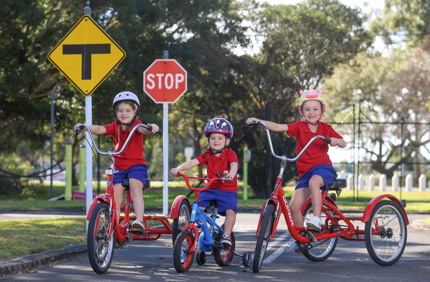 Children in uniform sitting on bikes outdoors