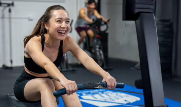 Woman sitting on a workout rower and smiling