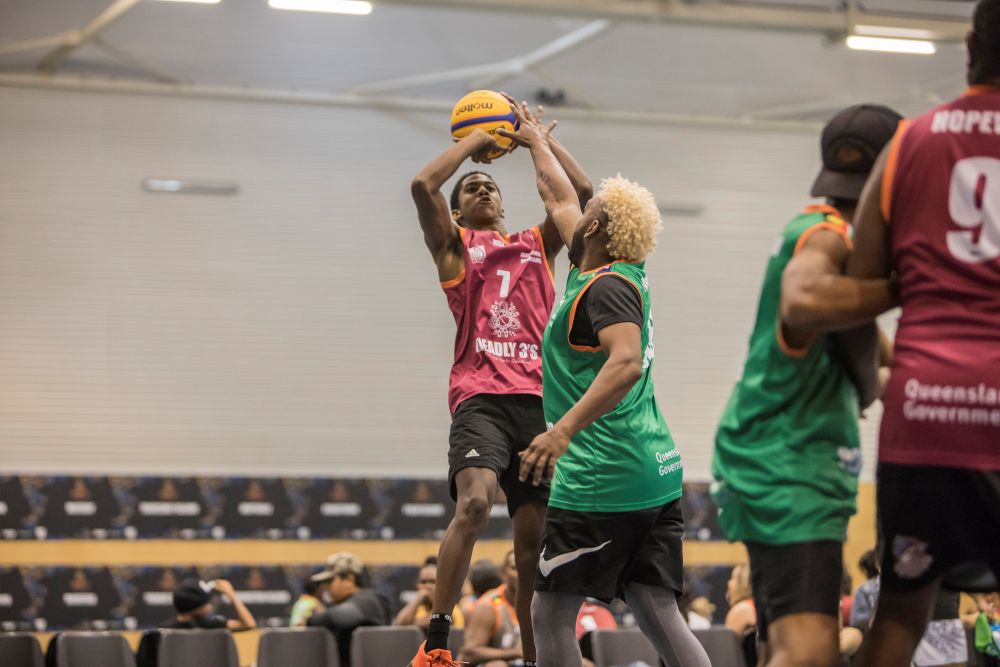 People on a basketball court, leaping into the air trying to shoot the ball