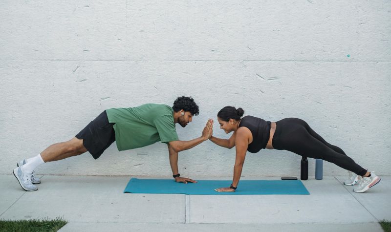 Man and woman facing each other planking while high fiving