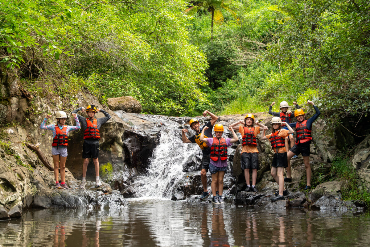PCYC team posing for picture on the riverbed near a waterfall