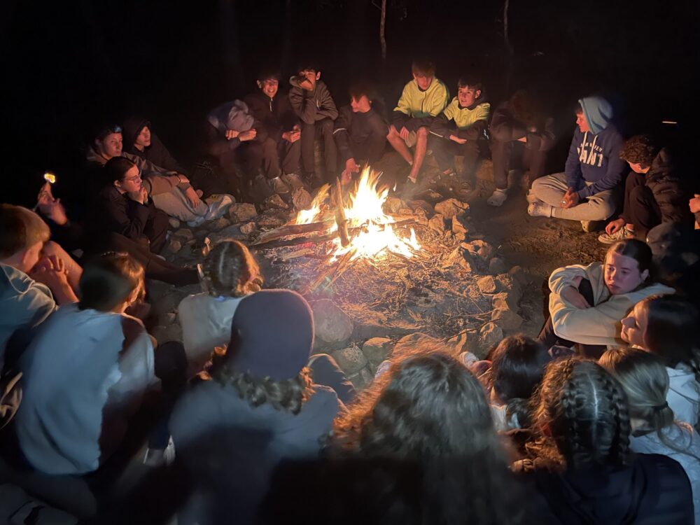 PCYC team sitting around bonfire in the camping program