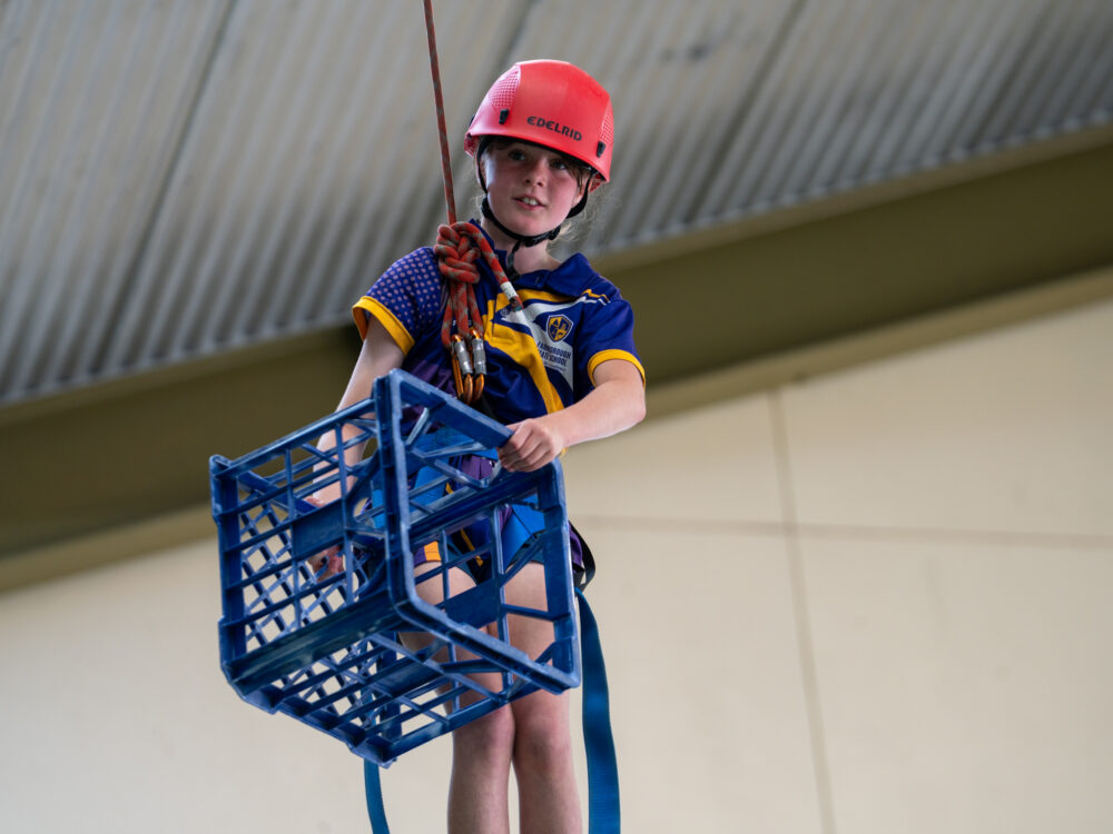 Boy swinging from rope and holding a crate - Indoor rope challenge